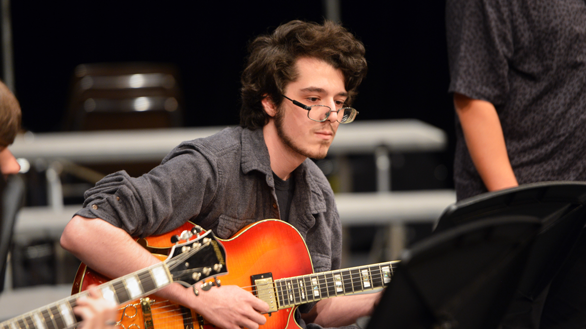 A male student plays an electric guitar